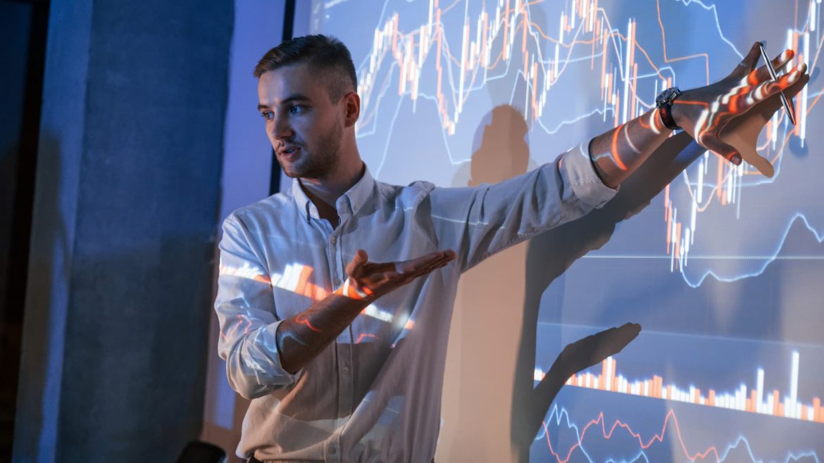 107338106-1700680360075-man-is-standing-near-projector-and-showing-graphs-2023-01-18-16-54-31-utc.jpg